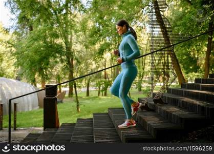 Morning workout in park, woman jogging by steps. Female runner goes in for sports at sunny day, healthy lifestyle, sportive girl on outdoors training. Morning workout in park, woman jogging by steps