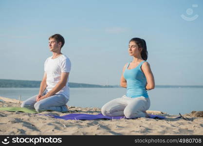 Morning Yoga Meditation at the Beach by young couple