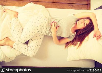 Mornings people concept. Sleepy woman sleeping in the bed. Attractive lady changing sleep positions.. Sleepy woman sleeping in the bed.