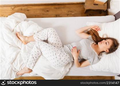 Mornings people concept. Sleepy woman sleeping in the bed. Attractive lady changing sleep positions.. Sleepy woman sleeping in the bed.