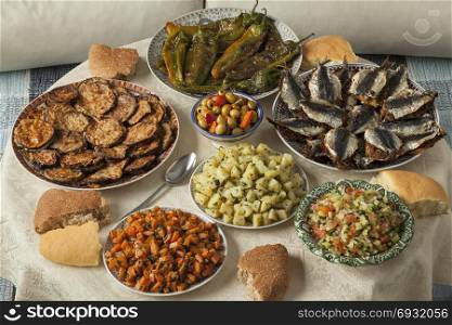 Moroccan meal with a variety of dishes with fresh cooked sardines, vegetables and bread