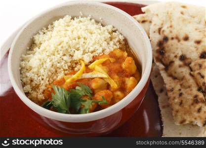 Moroccan style chickpea and tomato soup with plain couscous, garnished with lemon peel and parsley and served with kubz or kubus flat bread