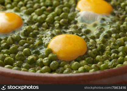 Moroccan tajine with green peas and sunny side up eggs close up