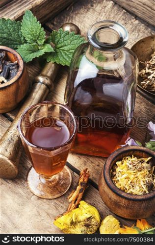 Mortar and bowl of raw and dried healing herbs.Assorted natural medical herbs. Healing herbs and bottle of elixir