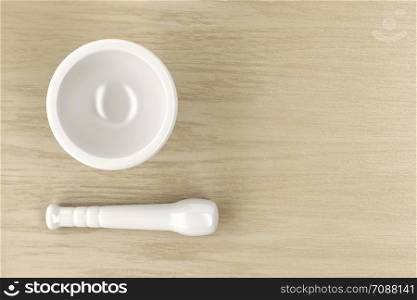 Mortar and pestle on wood table, top view