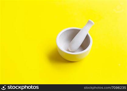 Mortar and pestle on yellow background. Copy space