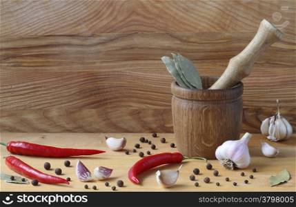 Mortar and pestle with pepper and spices on wooden table