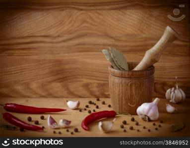 Mortar and pestle with pepper and spices on wooden table