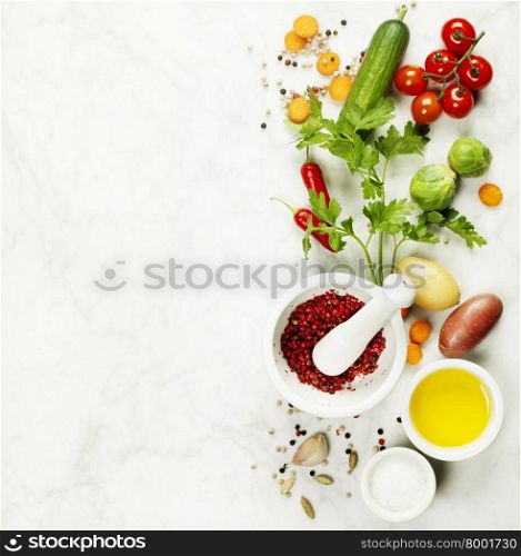 Mortar and pestle with various colorful spices and vegetables on marble table . Cooking, healthy or vegetarian eating concept. Background layout with free text space.