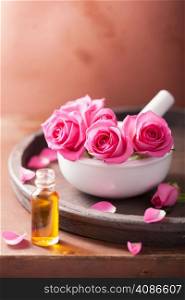 mortar with rose flowers and essential oil for aromatherapy and spa