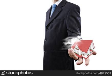 Mortgage concept. Close up of businessman holding house model in palm