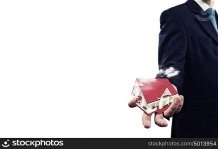 Mortgage concept. Close up of businessman holding house model in palm