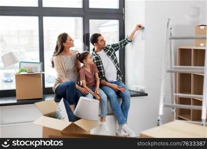 mortgage, family and real estate concept - happy mother, father and little daughter with color palette and stuff in boxes moving to new home. happy family with color palette moving to new home