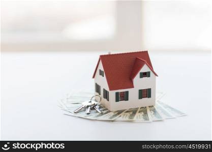 mortgage, investment, real estate and property concept - close up of home model, dollar money and house keys