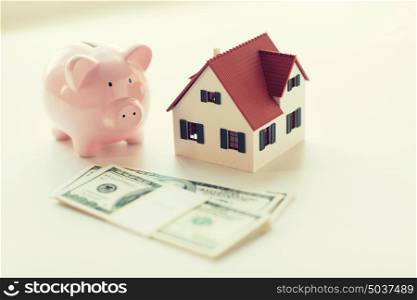 mortgage, investment, real estate and property concept - close up of home or house model, us dollar money and piggy bank. close up of house model, piggy bank and money
