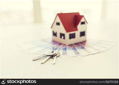 mortgage, investment, real estate and property concept - close up of home model, money and house keys. close up of home model, money and house keys