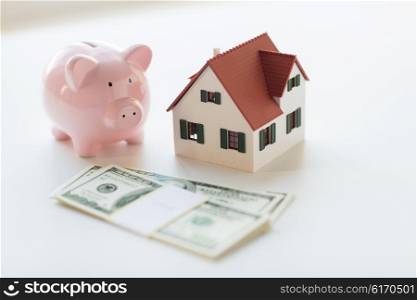 mortgage, investment, real estate and property concept - close up of home or house model, us dollar money and piggy bank