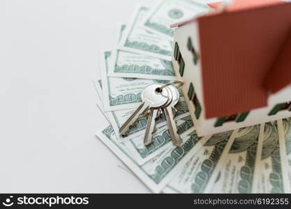 mortgage, investment, real estate and property concept - close up of home model, dollar money and house keys