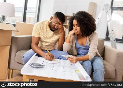 mortgage, moving and real estate concept - sad african american couple with blueprint and calculator counting money for repair costs to new home. sad couple with blueprint counting money at home