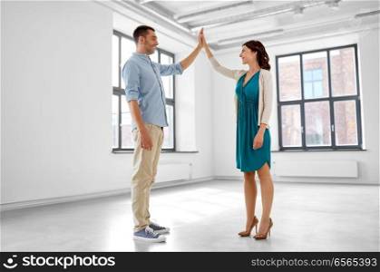 mortgage, people and real estate concept - happy couple at new home making high five gesture. happy couple making high five gesture at new home