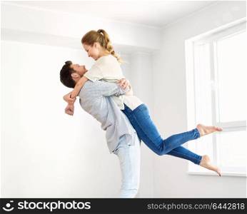 mortgage, people and real estate concept - happy couple hugging at empty room of new home. happy couple at empty room of new home