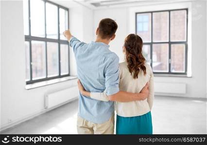 mortgage, people and real estate concept - happy couple hugging at new home from back. happy couple hugging at new home