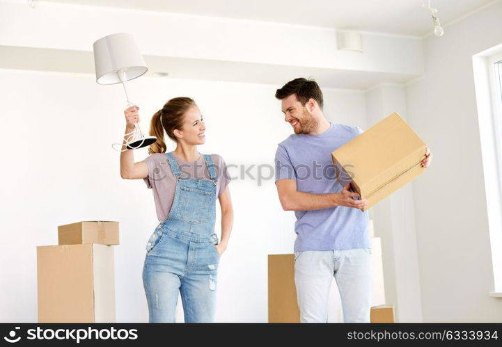 mortgage, people and real estate concept - happy couple with boxes and lamp moving to new home. couple with boxes and lamp moving to new home