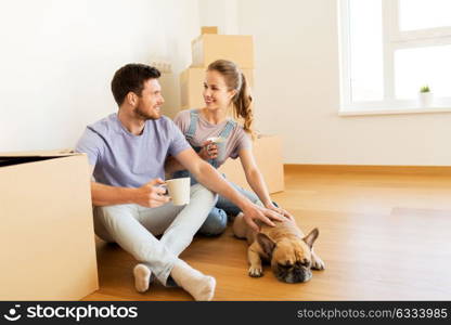 mortgage, people and real estate concept - happy couple with boxes and french bulldog dog moving to new home and drinking coffee . happy couple with boxes and dog moving to new home