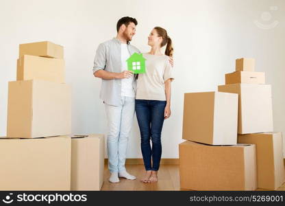 mortgage, people and real estate concept - happy couple with green paper house and boxes moving to new home. happy couple with boxes moving to new home