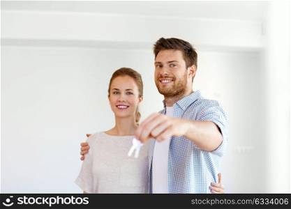 mortgage, people and real estate concept - happy couple with keys at empty room of new home. happy couple with keys of new home