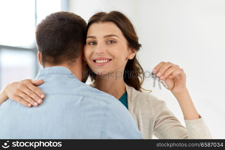 mortgage, people and real estate concept - happy couple with keys at empty room of new home. happy couple with keys of new home