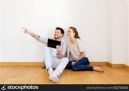 mortgage, people and real estate concept - happy couple with tablet pc computer at empty room of new home. happy couple with tablet pc computer at new home