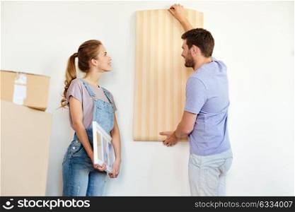 mortgage, people and real estate concept - happy couple with wallpaper repairing apartment or moving to new home. couple with wallpaper repairing apartment or home