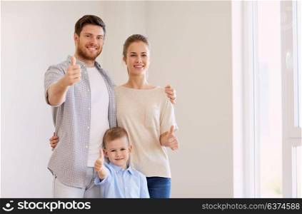 mortgage, people and real estate concept - happy family with child moving to new home and showing thumbs up. happy family with child moving to new home