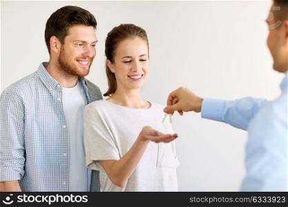 mortgage, people and real estate concept - realtor giving keys from new apartment or home to happy couple. realtor giving keys from new home to happy couple