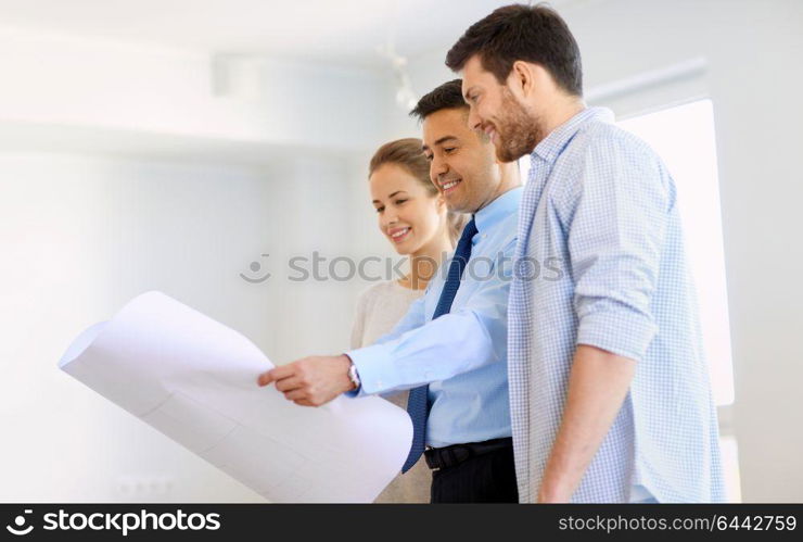 mortgage, people and real estate concept - realtor showing blueprint of new home to happy couple. realtor showing blueprint of new home to couple