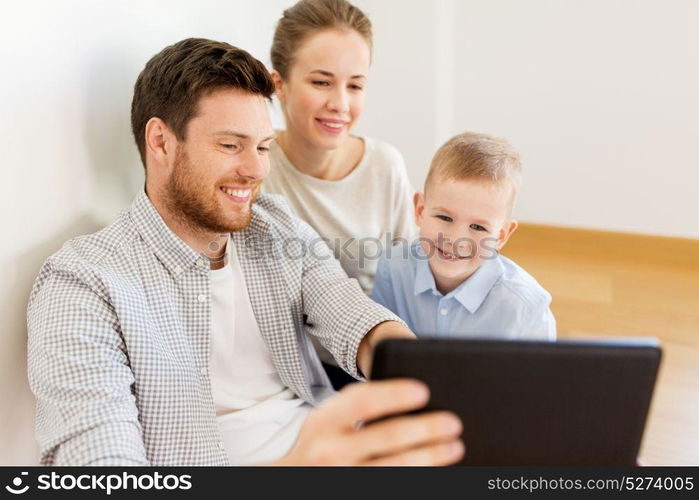 mortgage, people, housing and real estate concept - happy family with tablet pc computer moving to new home. happy family with tablet pc moving to new home