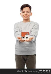 mortgage, real estate and accommodation concept - smiling boy holding house model over white background. smiling boy holding house model