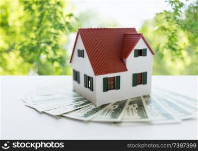 mortgage, real estate and property concept - close up of home or house model and money over green natural background. close up of home or house model and money
