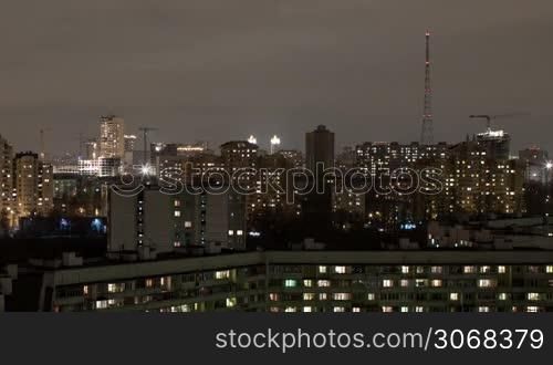 Moscow high angle aerial view industrial time lapse by night with cranes, car traffic and TV tower shot with long exposure with blurred car lights