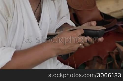 "Moscow historical festival "Times and epoch" in Colomna. Shoemaker sews the shoes with his hands."