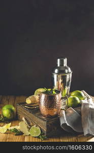 Moscow mule alcoholic cocktail in copper mug with crushed ice, mint and lemon over minton dark wooden table with amazing backlight, copy space. Close up view, copy space