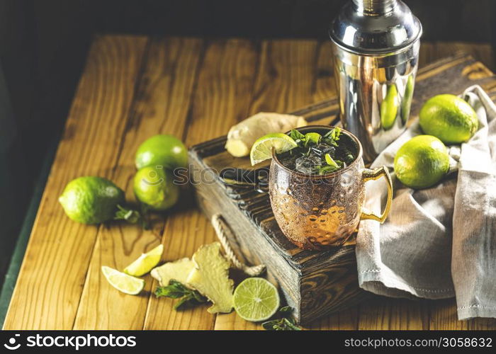 Moscow mule alcoholic cocktail in copper mug with crushed ice, mint and lemon over minton dark wooden table with amazing backlight, copy space. Close up view, copy space