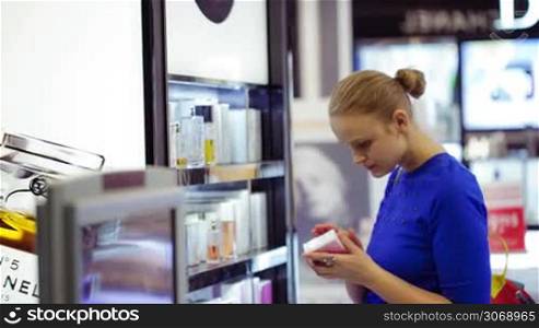 MOSCOW, RUSSIA - JANUARY 27, 2014: Young woman choosing a perfume in duty free area at Domodedovo airport