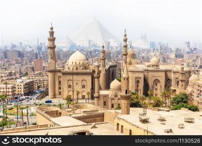 Mosque-Madrassa of Sultan Hassan and the Pyramids in the mist, Cairo, Egypt.. Mosque-Madrassa of Sultan Hassan and the Pyramids in the mist, Cairo, Egypt