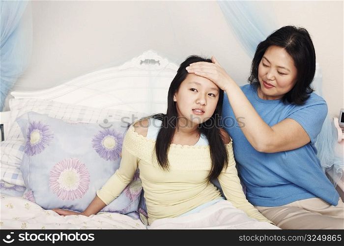 Mother&acute;s hand on her daughter&acute;s forehead