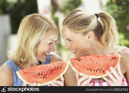 Mother And Adult Daughter Enjoying Slices Of Water Melon