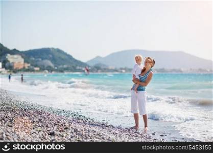 Mother and baby at sea shore looking on copy space