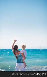 Mother and baby at sea shore pointing up on copy space