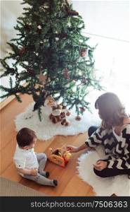 Mother and baby decorating and playing around the Christmas Tree